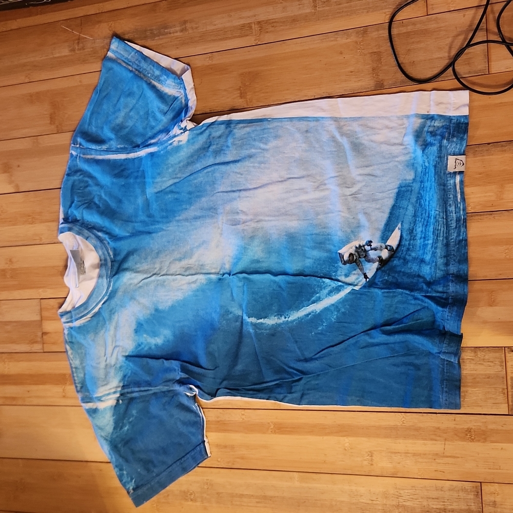 Tie dye t-shirt with a picture of astronaut surfing.